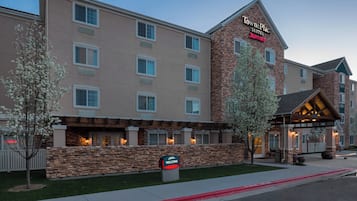 Experience the warm welcome at TownePlace Suites, featuring a modern design with a landscaped entrance and inviting facade.