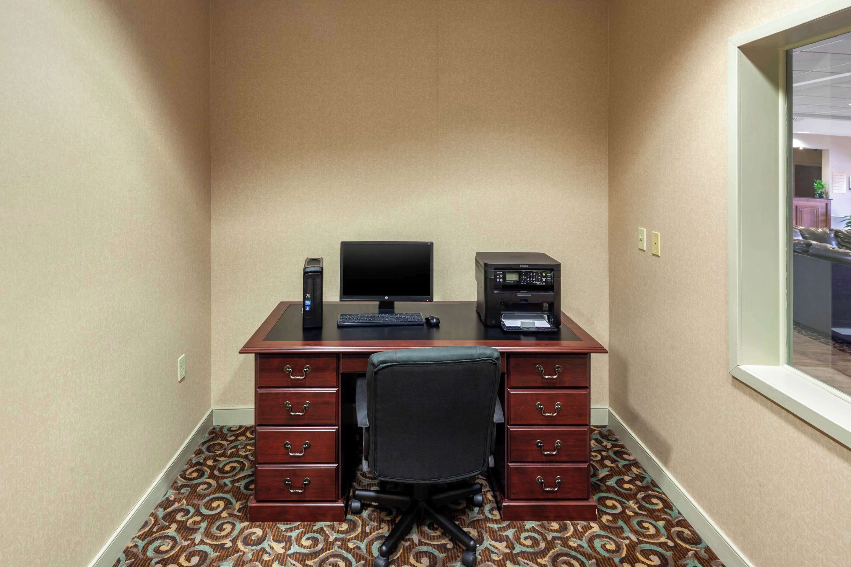 A small office with a desk, computer, printer, and chair.