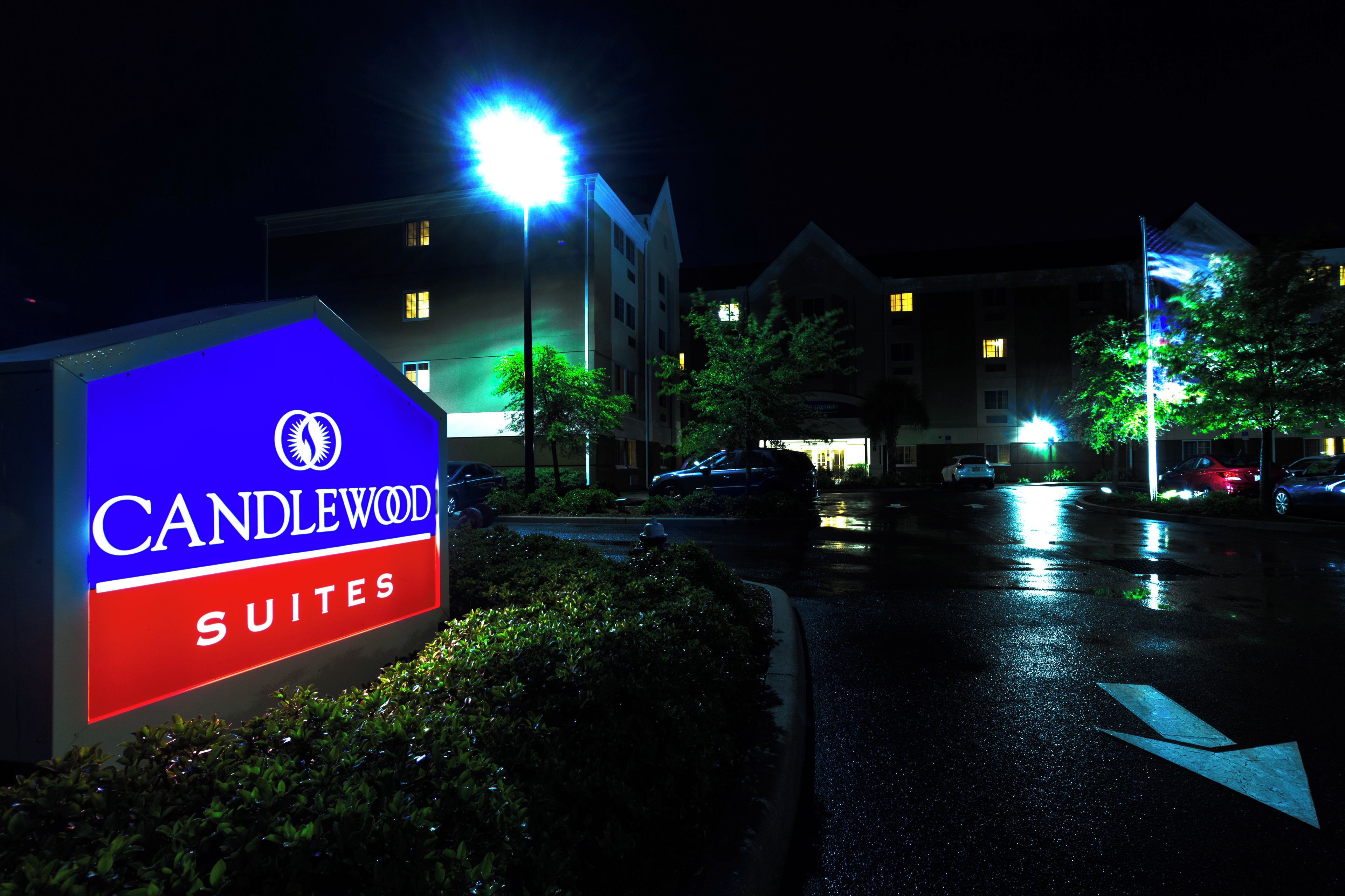 Een hotelsbord met de naam 'CANDLEWOOD SUITES' en een nachtzicht van de hotelgebouwen.
