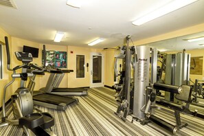 Une salle de sport équipée de tapis de course, d’un vélo d’appartement et d’appareils de musculation.