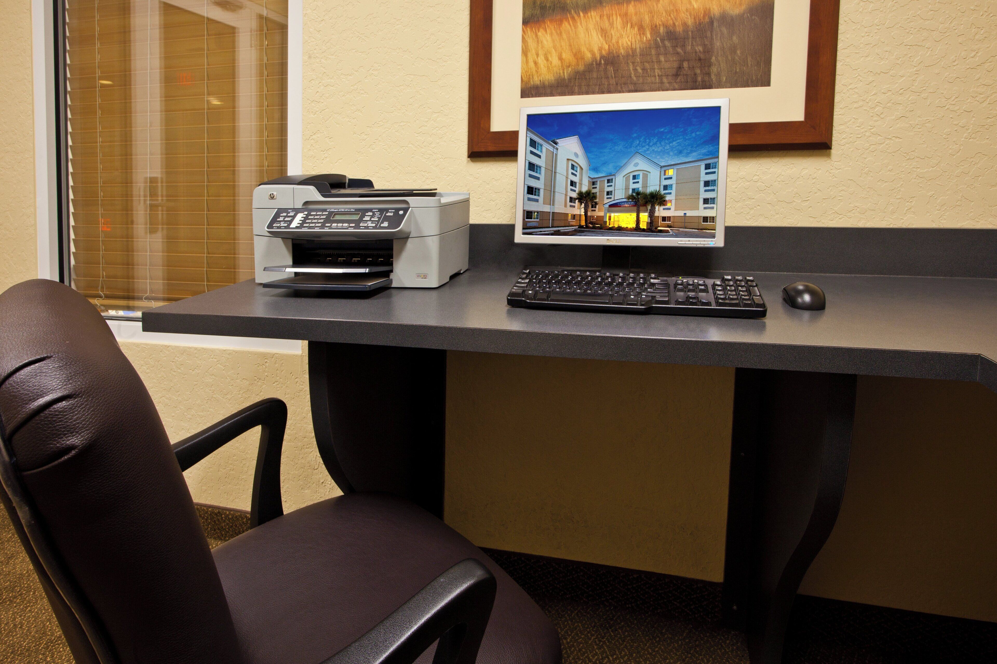 A desk with a printer, a computer monitor, a keyboard, and a mouse.