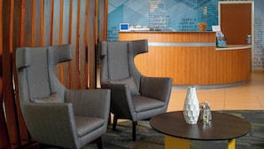 Un área de recepción con dos sillones grises, un mostrador de recepción y una pared con texto y diseños geométricos.