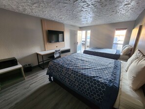 A hotel room with a large bed, a desk with a flat-screen TV, a chair, and a window with a view of the outside. - Americas Best Value Inn Longview (Longview)