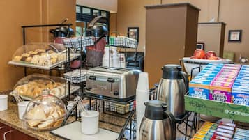 A breakfast buffet with various food items, a toaster, coffee maker, and cereal boxes.
