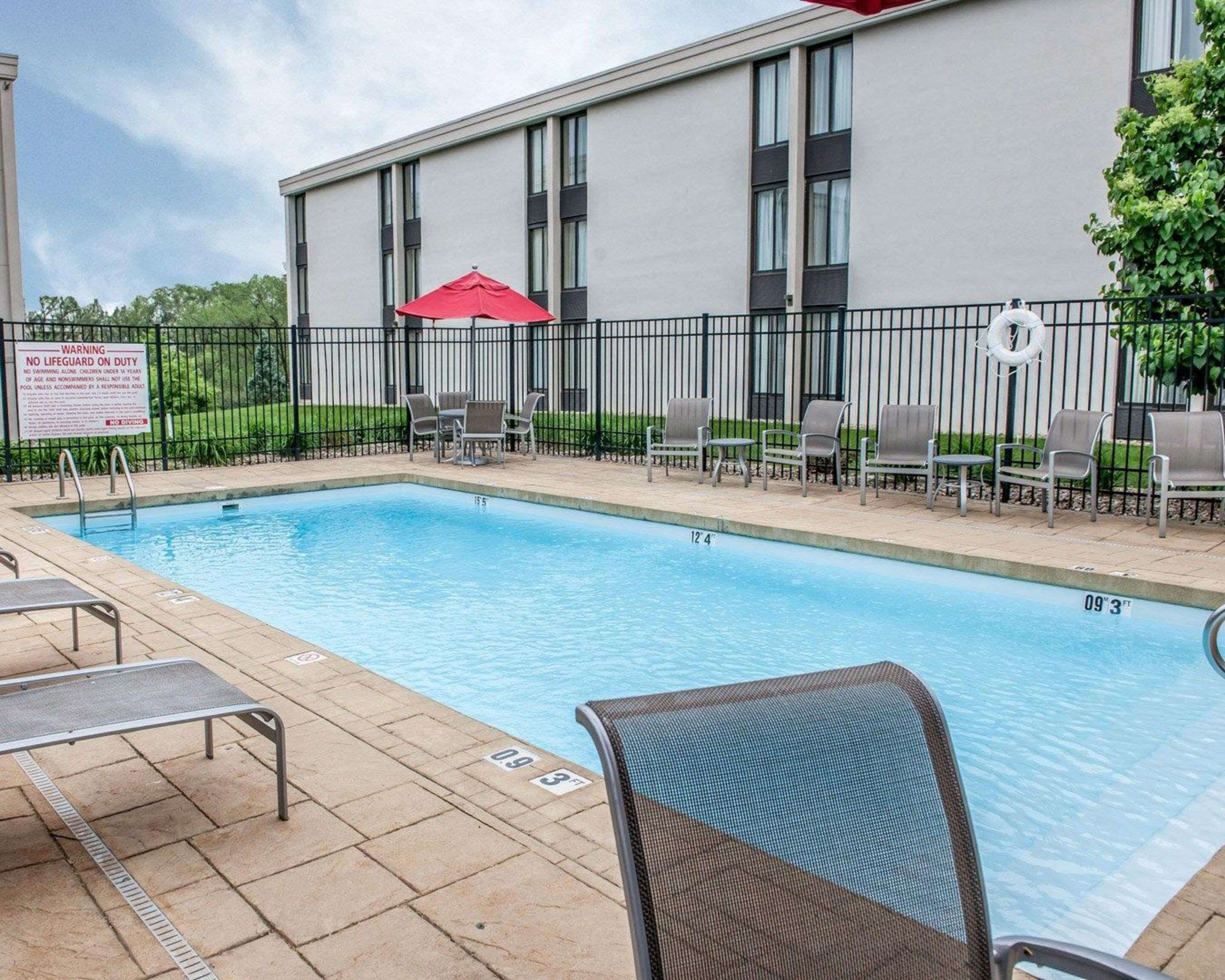 A swimming pool with lounge chairs and a lifeguard sign.