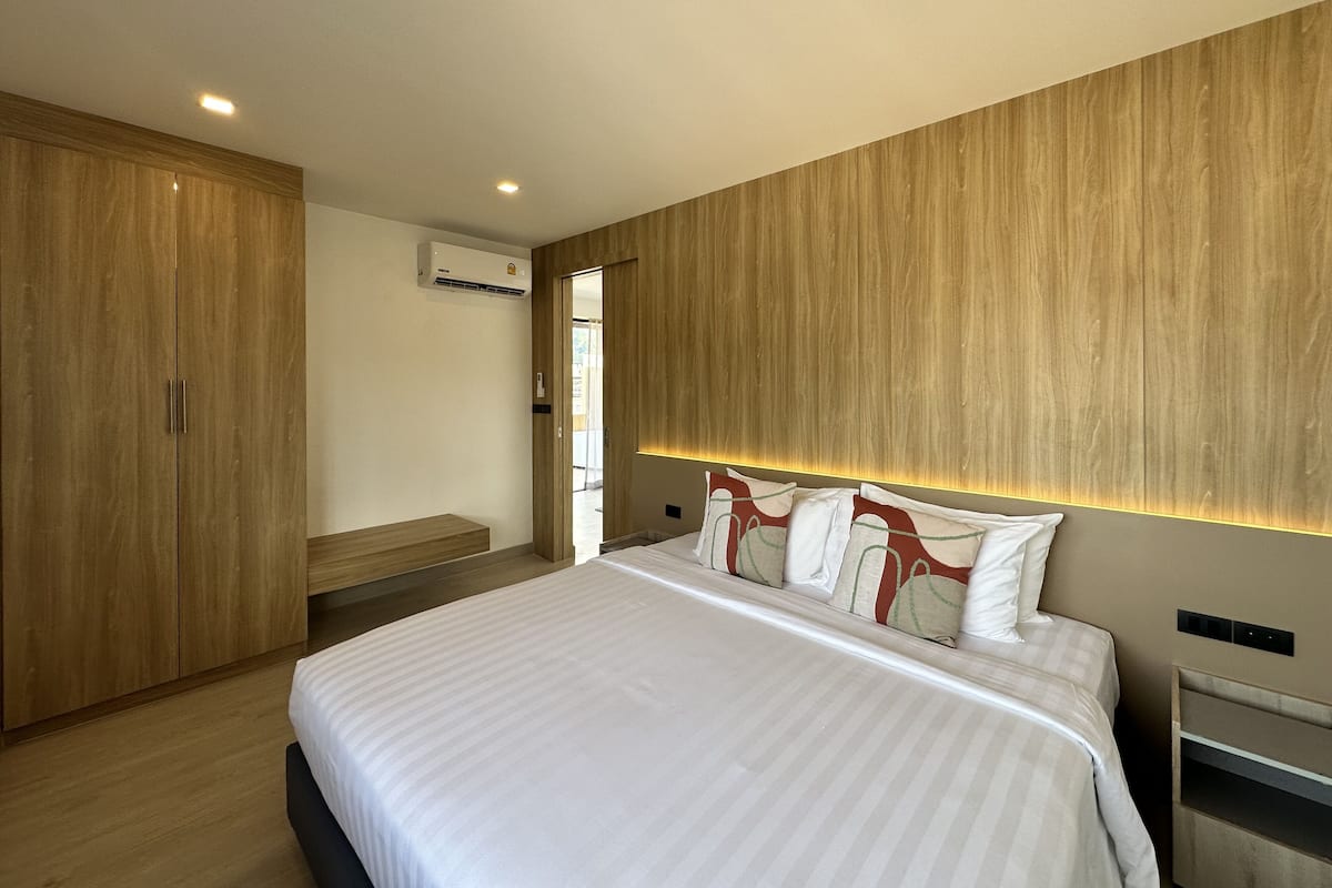 Un dormitorio moderno con una cama grande, un armario de madera e iluminación empotrada.