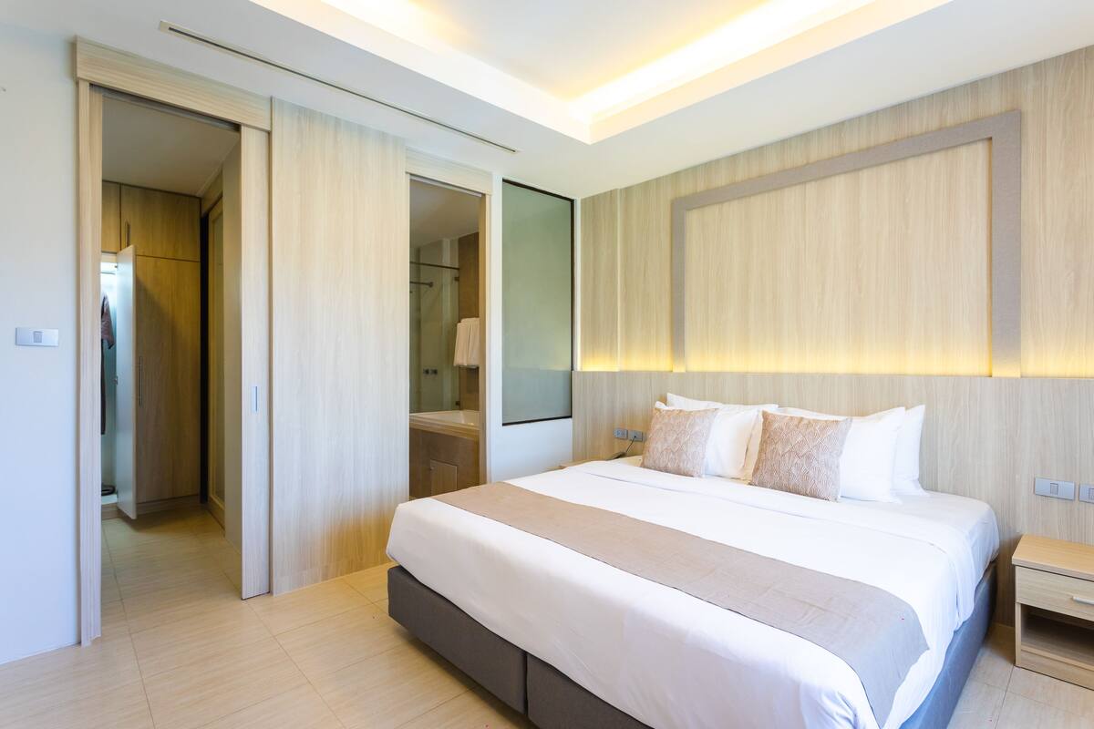Un dormitorio moderno con una cama grande, una mesita de noche, un espejo y un vestidor.