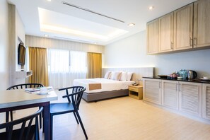 A modern hotel room with a bed, bedside table, and a kitchenette area. - Coconut Village Resort (Patong)