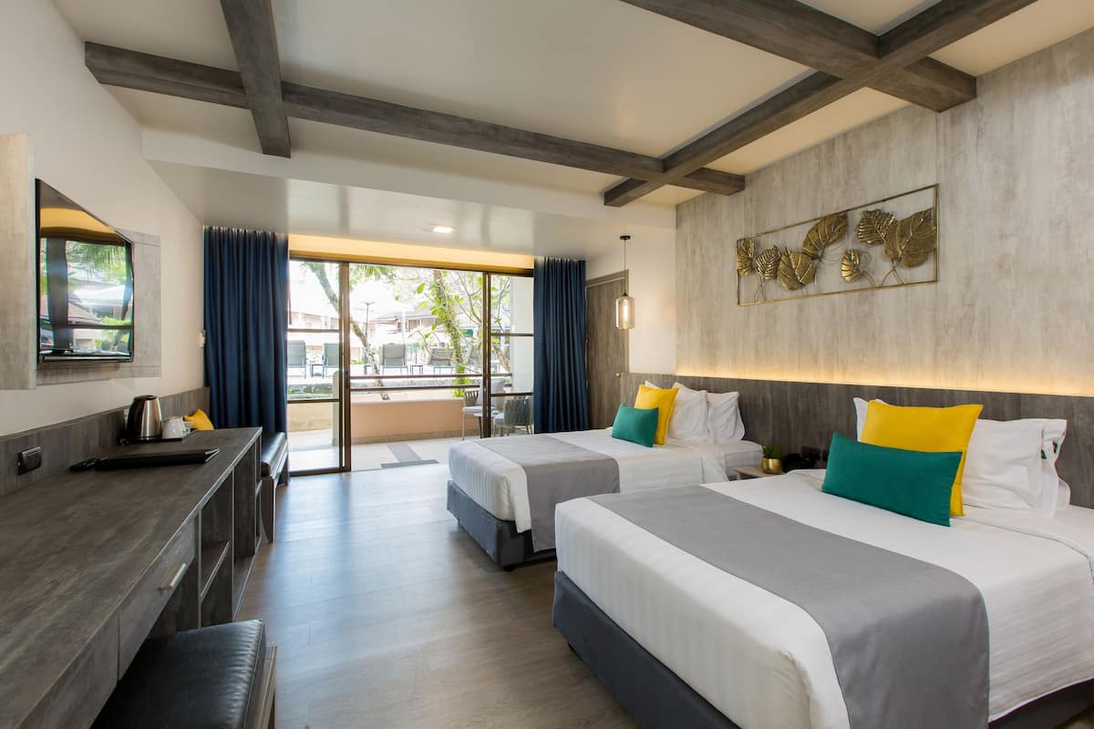 Habitación de hotel con dos camas, un escritorio y un ventanal grande.