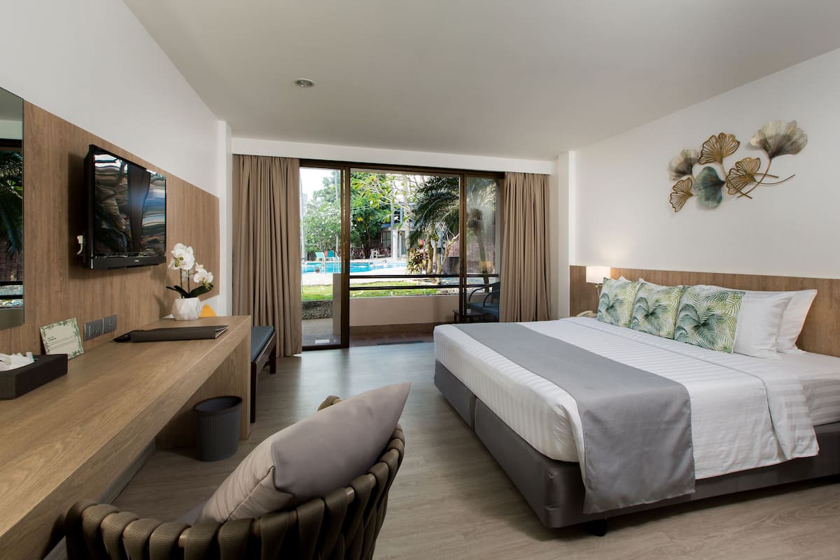 Una habitación de hotel moderna con una cama grande, un escritorio, una silla y un televisor.