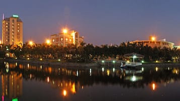 A hotel with a reflection in the water, a boat, and a gazebo.