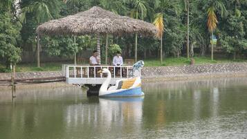 Paseo en bote con una cubierta de paja, pasajeros y una masa de agua tranquila rodeada de vegetación.