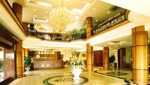 A hotel lobby with a reception desk, a large chandelier, and a central floral arrangement. - Camela Hotel & Resort (Hai Phong)