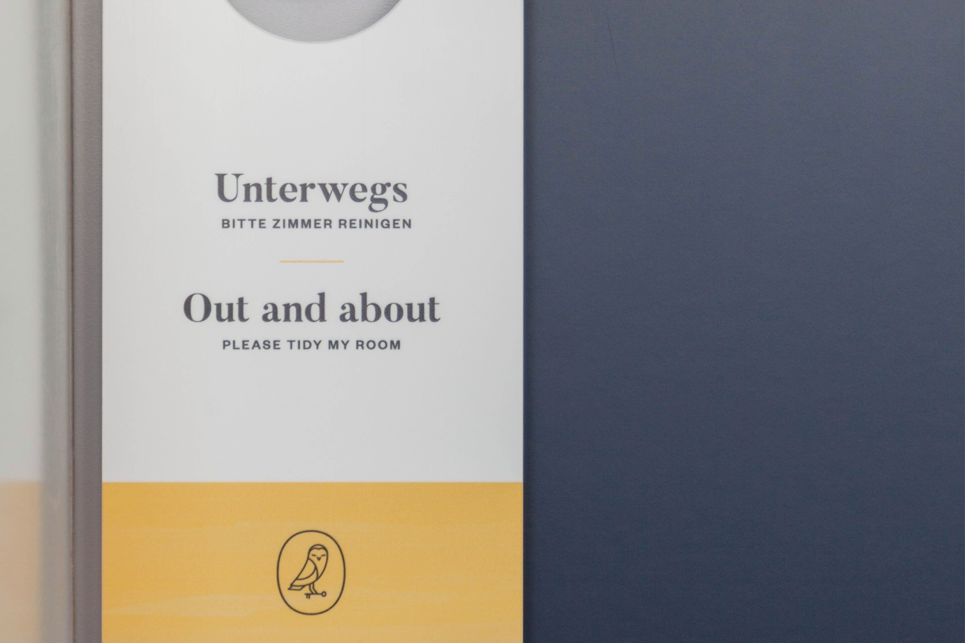 A hotel room sign with 'Unterwegs Bitte Zimmer Reinigen' and 'Out and about Please tidy my room' instructions.