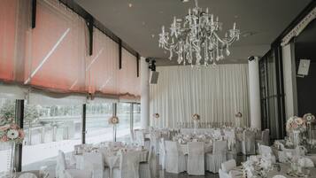 A banquet hall with round tables, white tablecloths, and floral centerpieces.