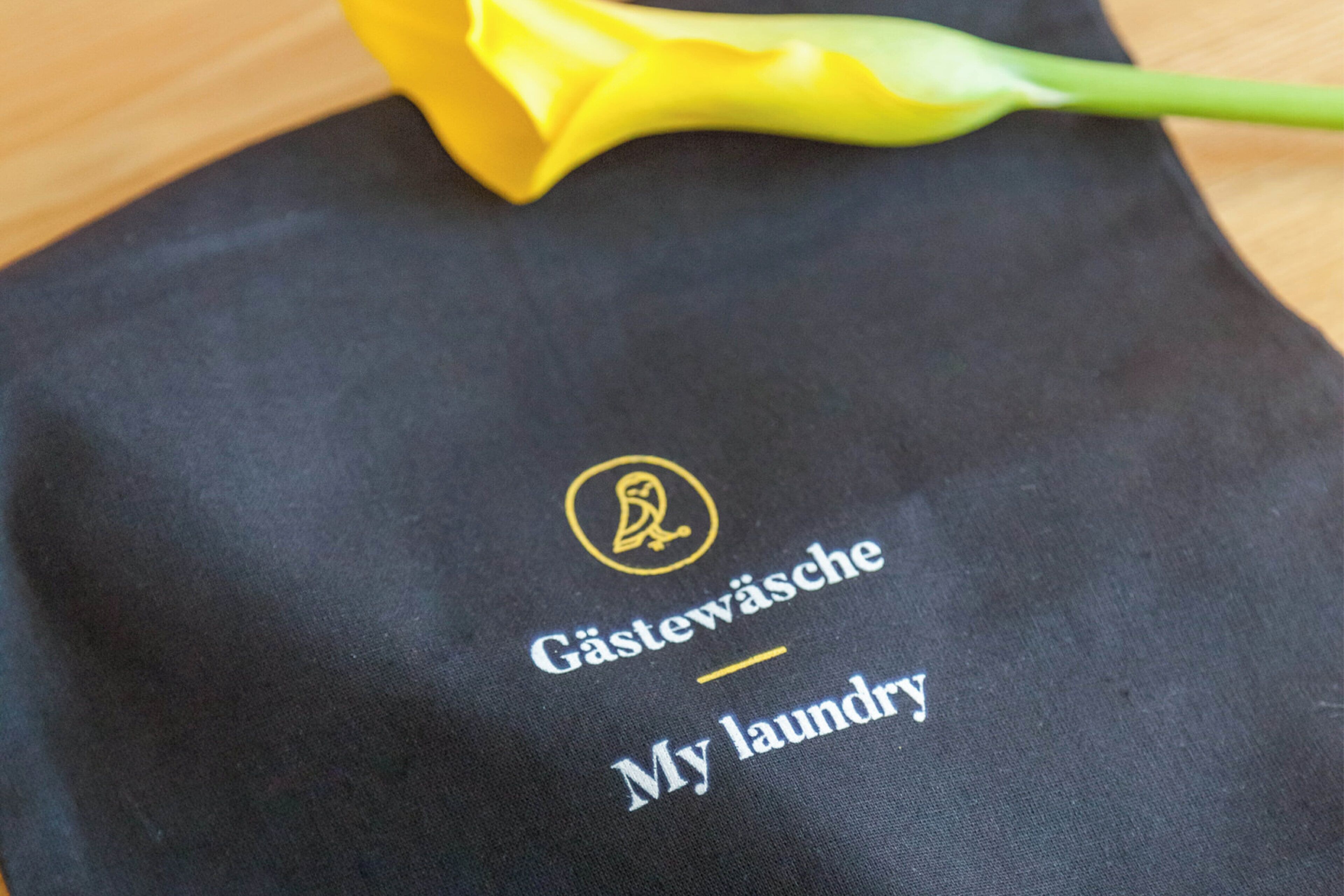 A black cloth with embroidered text and a logo, likely a branded item.