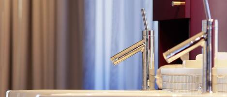 A modern bathroom with a white sink, chrome faucet, and a mirror.