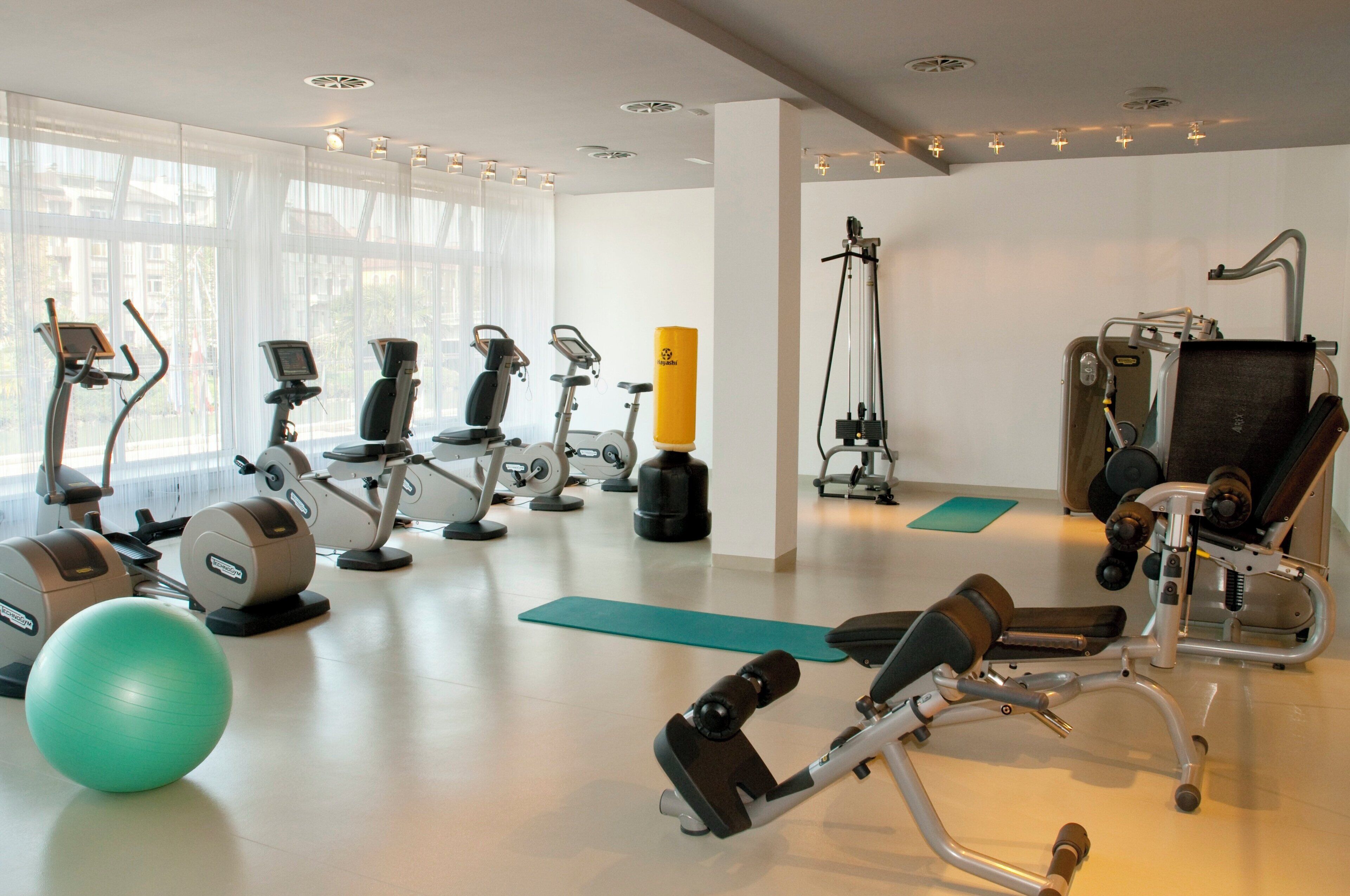 Ein Fitnessstudio mit unterschiedlichen Trainingsgeräten, darunter Laufbänder, Crosstrainer und Kraftgeräte.