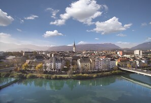 A riverside town with historic buildings, a prominent church, and mountains in the background.