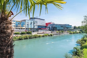 A river with buildings in the background, including a modern structure with a glass facade.