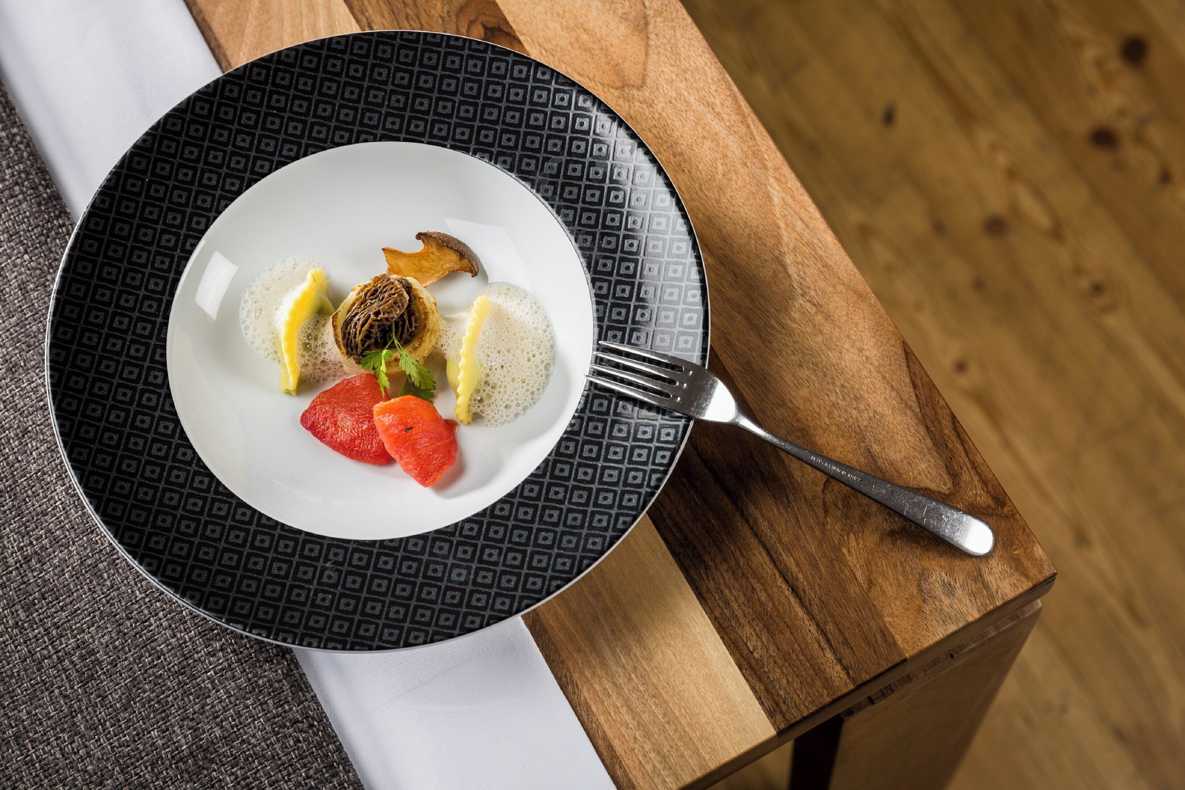 A plate of food with a fork on a wooden table.