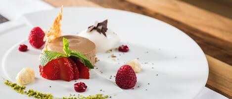 Prato de sobremesa com mousse de chocolate, morangos, framboesas e folhas de hortelã.