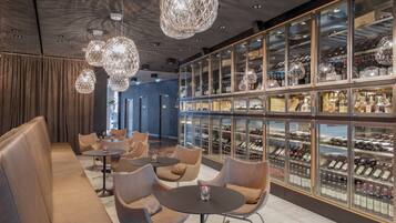 A modern bar area with leather seating, hanging crystal chandeliers, and glass-fronted wine racks.