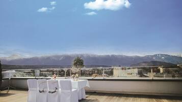 Terraza en la azotea con una mesa preparada para comer, con vistas a un paisaje montañoso.