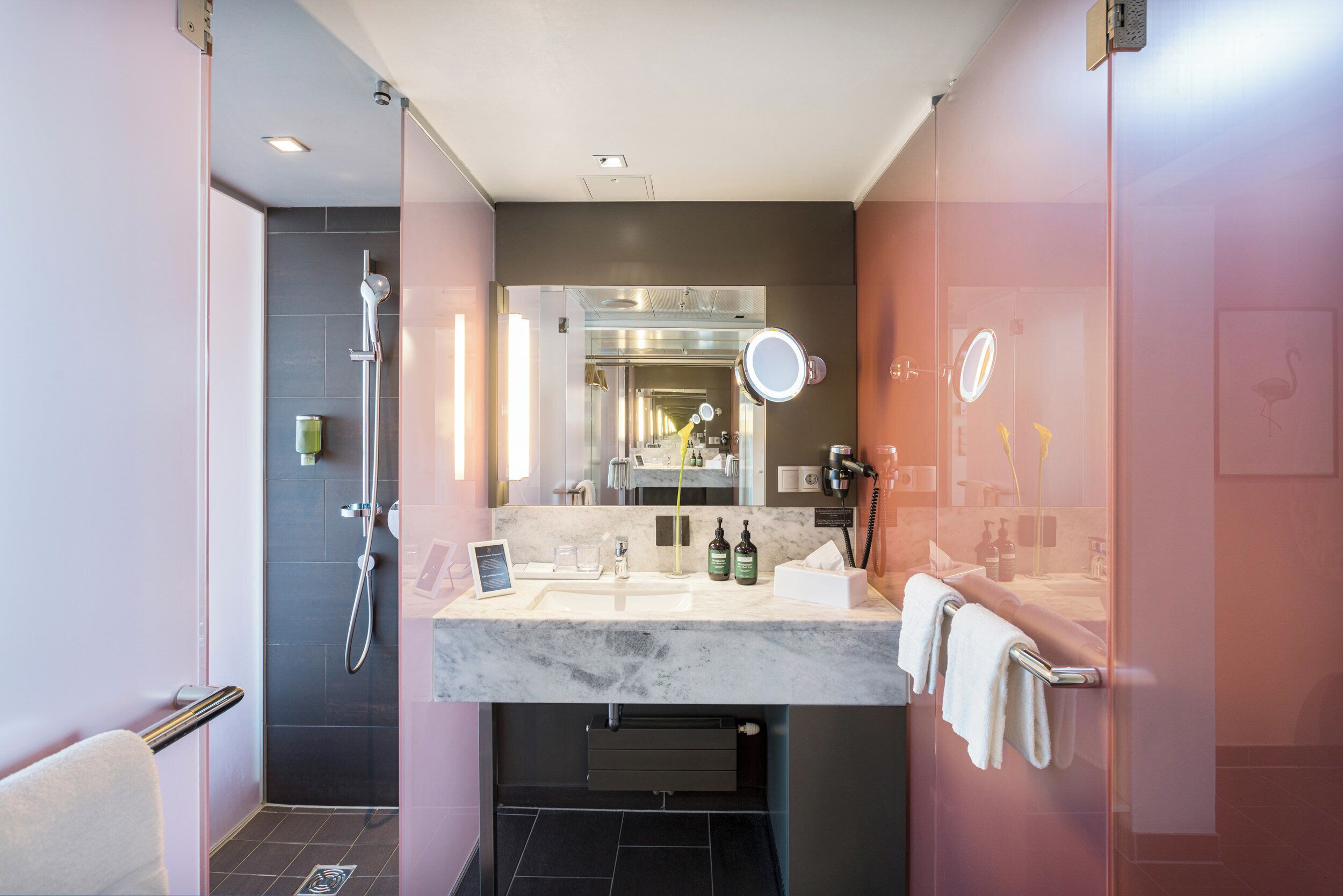 A modern bathroom with a glass shower enclosure, a vanity with a marble countertop, and a large mirror.