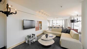 Ein modernes Wohnzimmer mit einem Flachbildfernseher, einer Couch, einem Couchtisch und einem Bücherregal.