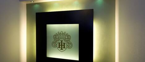 Logotipo iluminado montado en la pared con una corona y un emblema de 'H'.