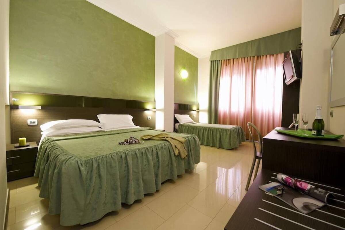 A hotel room with two beds, a desk, and a chair.