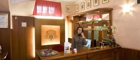 Un área de recepción con un mostrador de madera, un emblema enmarcado encima y un mostrador que exhibe productos de panadería.
