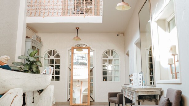 A spacious interior with a high ceiling, a balcony with wrought iron railings, a large mirror, and a patterned floor.