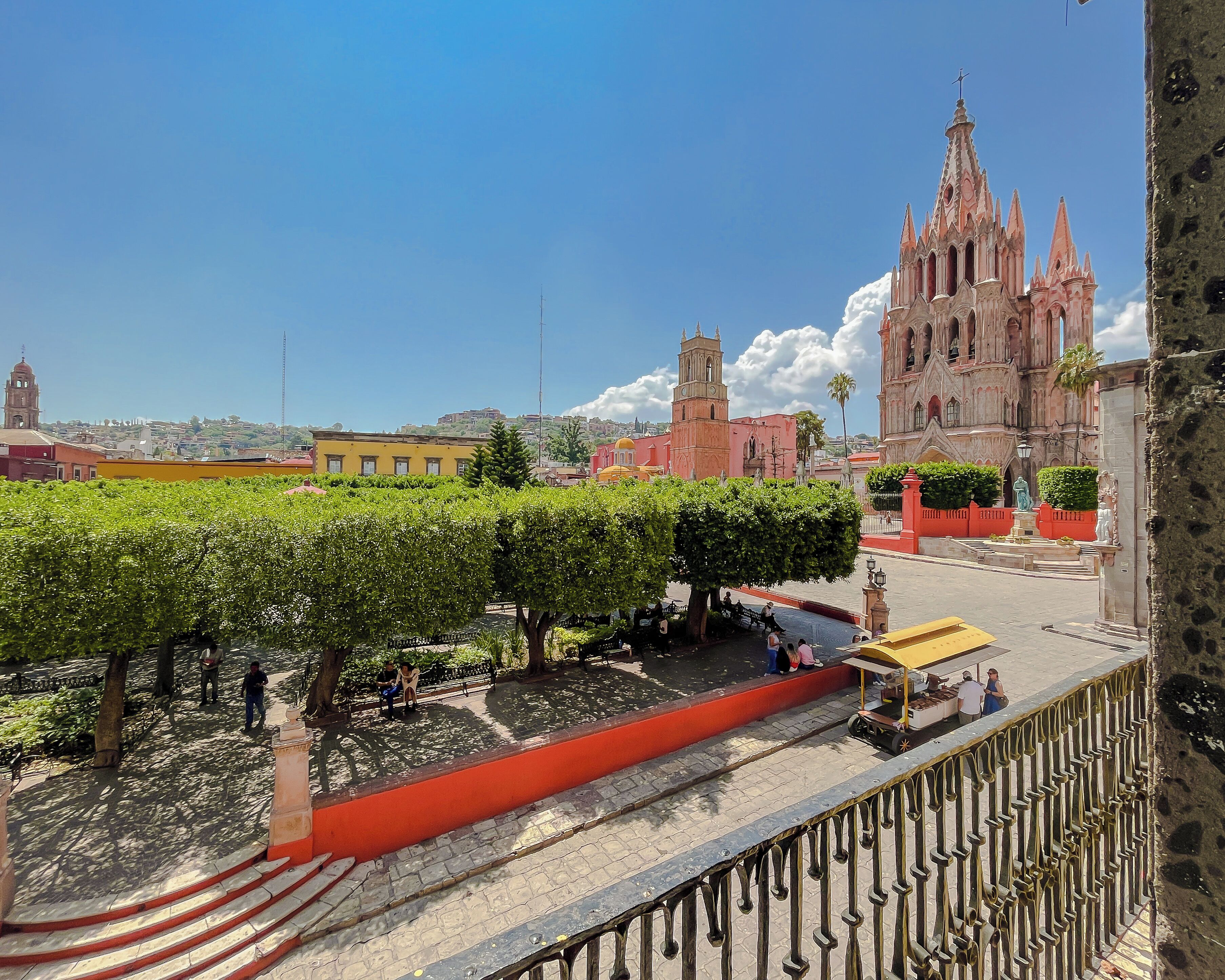 Un patio con un sendero rojo, una fuente y un carrito de ventas.