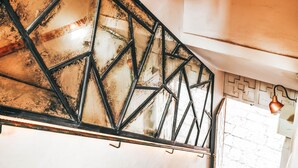A staircase with a geometric metal railing and a modern light fixture above.