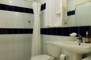 A bathroom with a white toilet, a white sink, a shower curtain, and a mirror.