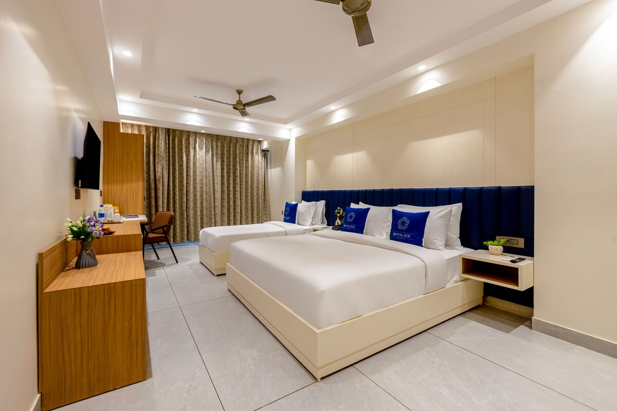 A hotel room with a large bed, a desk, a chair, and a ceiling fan.