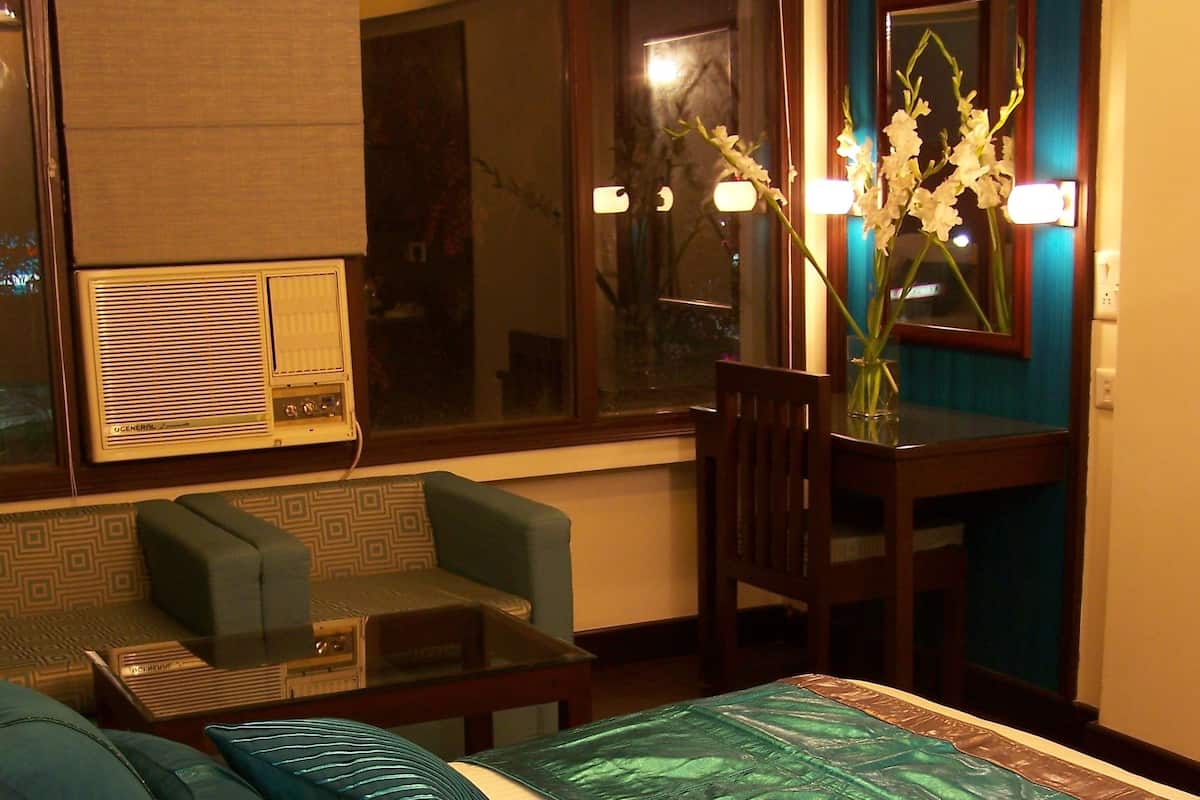 A hotel room with a bed, a desk, a chair, a window, and a mirror.
