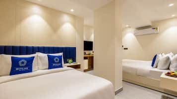A hotel room with two beds, a bedside table, a small desk, and an air conditioning unit.