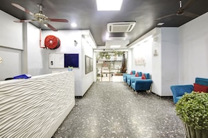 A reception area with a reception desk, blue seating, a ceiling fan, and a glass door leading to an outdoor area.