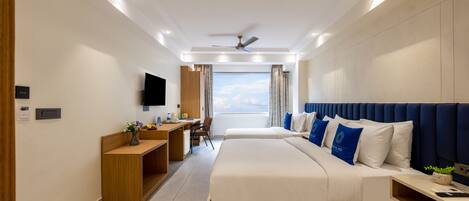 A modern hotel room with a large bed, a desk, a flat-screen TV, and a ceiling fan.