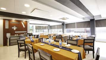 A dining area with tables set for meals, chairs, and a counter with a cross design on the wall.