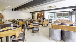 A dining area with multiple tables and chairs, equipped with water bottles and glasses. - Hotel BB Palace (New Delhi)
