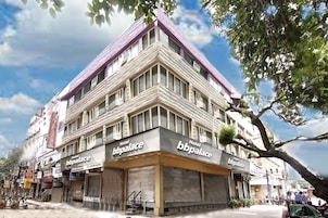 A corner building with multiple 'bbpalace' hotel signs, large windows, and a tree in the foreground.