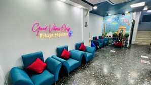 A hotel lobby with blue chairs, a neon sign, and a mural of Delhi landmarks. - Hotel BB Palace (New Delhi)