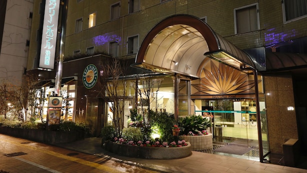 A hotel entrance with a glass facade, a covered outdoor area, and a signboard. - Tokyo Green Hotel Korakuen (Tokyo)