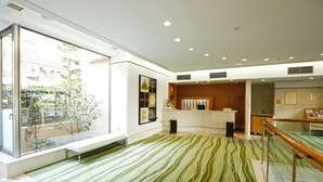 A modern hotel lobby with a large glass window, a reception desk, and a patterned carpet. - Tokyo Green Hotel Korakuen (Tokyo)
