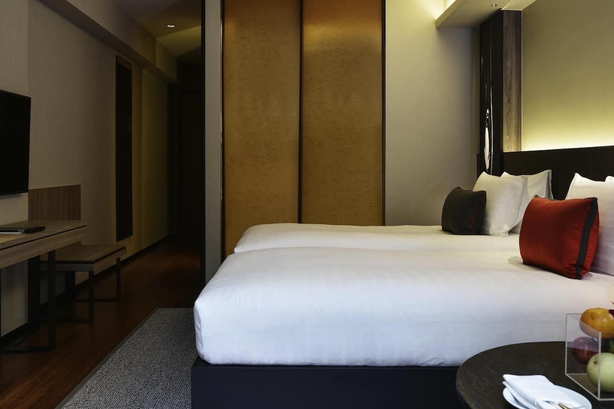 Una habitación de hotel con una cama grande, un escritorio, televisión y una mesita con fruteros.