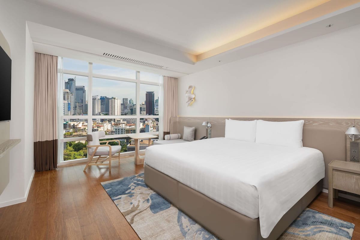 Una habitación de hotel moderna con una cama grande, un escritorio y vistas a la ciudad.